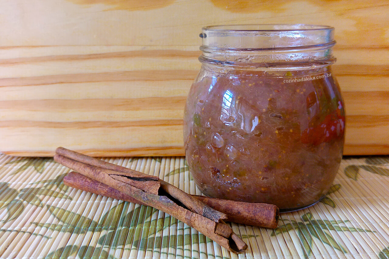 Potinho de vidro com geléia de figo. Ao lado do potinho, uma rama de canela.