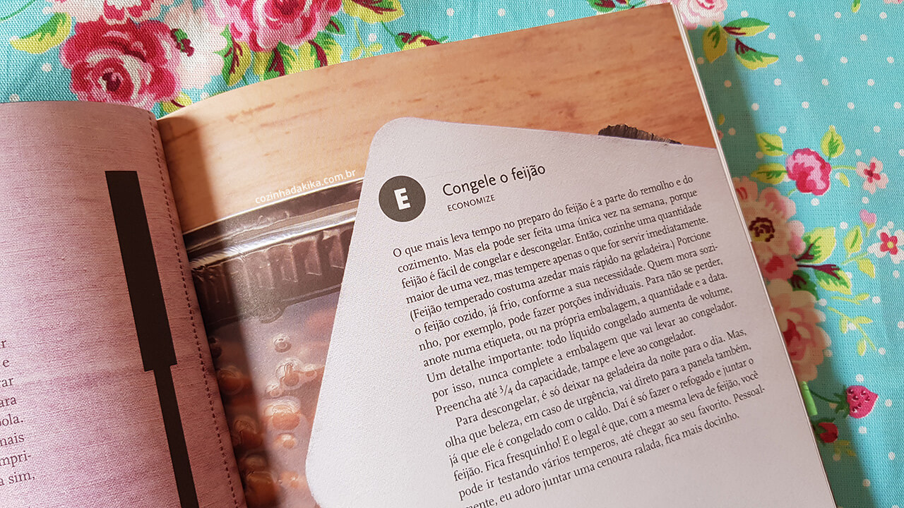 Livro Cozinha Prática da Rita Lobo, sobre um tecido florido. O livro está aberto numa página sobre congelamento de feijão.