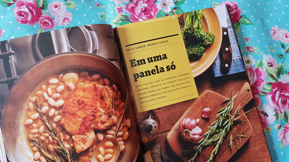 Livro "Só Para Um" da Rita Lobo, sobre um tecido florido, aberto numa página que fala sobre cozinhar sujando apenas uma panela