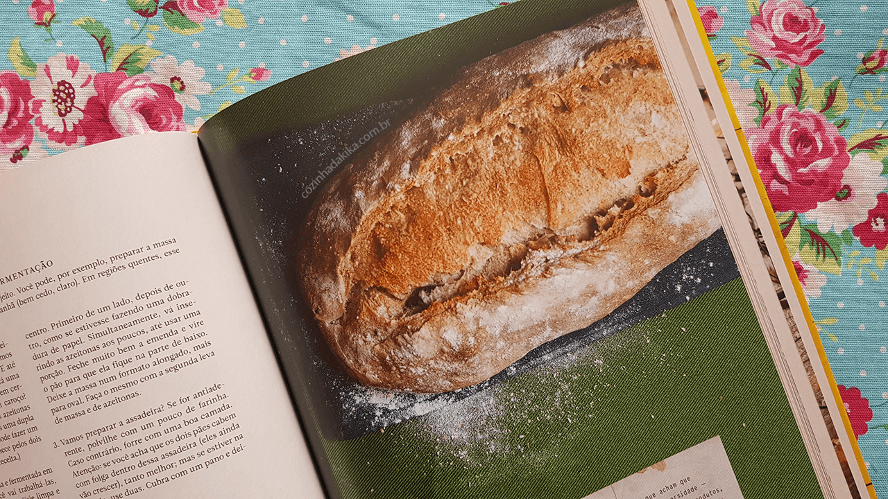 Livro Pão Nosso, do Luiz Américo Camargo. A foto mostra o livro aberto - numa página a receita de pão, e na outra a foto desse pão.